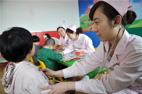 A volunteer from a local hospital in Handan city, Hebei province, checks the health of a child who suffers from autism, on April 1. Caring for autistic children