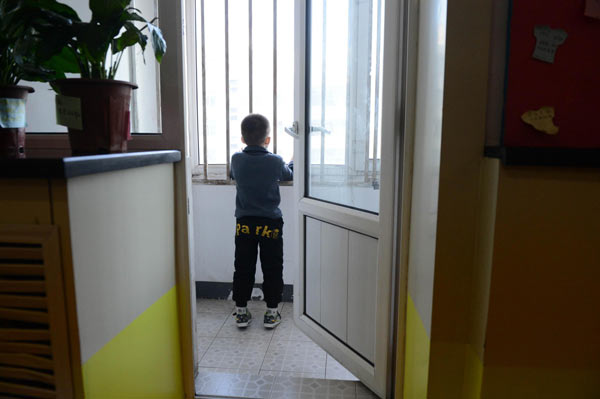 A child suffering from autism looks outward on a balcony of classroom in a rehabilitation center in Harbin city, Northeast China's Heilongjiang provine on March 28, 2013. Caring for autistic children