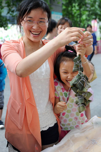 A mother and her daughter react during a zongzi-making contest in Hangzhou, East China's Zhejiang province, June 11, 2013. Dragon Boat Festival celebrated around the country