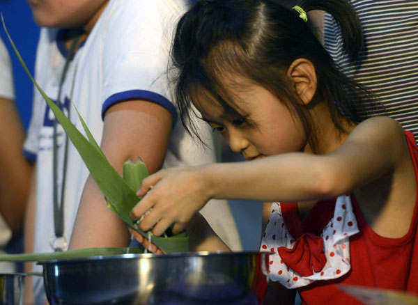 A girl learns how to make zongzi during a Dragon Boat Festival activity in Urumqi, Northwest China's Xinjiang Uygur autonomous region, June 11, 2013. Dragon Boat Festival celebrated around the country