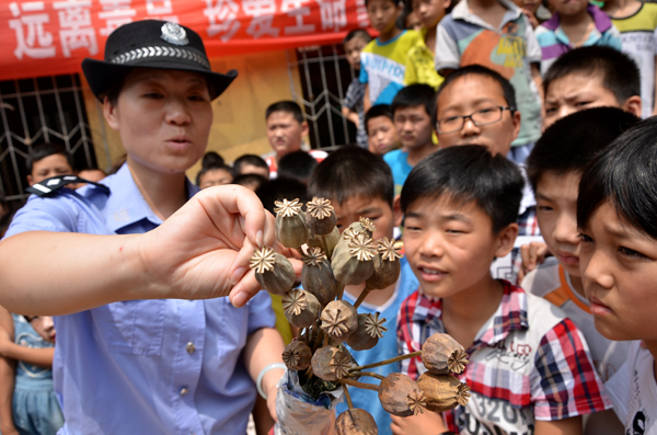 A policewoman explains the power of poppy, the plant opium is made from, at Wenfeng Elementary School in Xuchang, Henan province, on June 25, 2013. Anti-drug campaigns around China