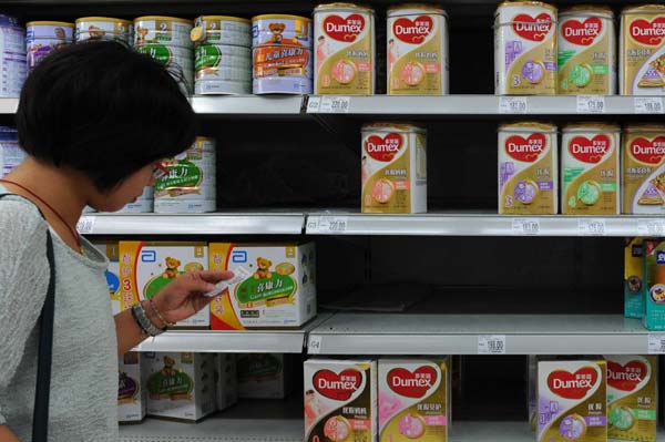 A woman checks prices beside a shelf of Dumex baby formula at a store in Yichang, in central China's Hubei province. Many shops in Beijing and Shanghai take the product off the shelves. AFP Fonterra says sorry for 'anxiety'