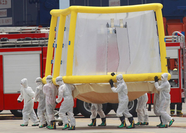 Soldiers in biohazard suits carry a disinfecting shower while simulating a mock contamination of a ship during the 2011 Jinhua exercise at the Port of Taipei in New Taipei City, northern Taiwan June 29, 2011. Disaster-response drill in Taiwan