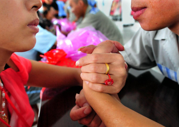 An inmate holds his fiancée's hand while celebrating the upcoming Chinese Valentine's Day, Qixi Festival, which falls on the seventh day of the seventh month on the Chinese lunar calendar, August 6 this year, at a prison in Xinyang, Central China's Henan province, August 3, 2011. Celebrating Chinese Valentine's Day behind bars