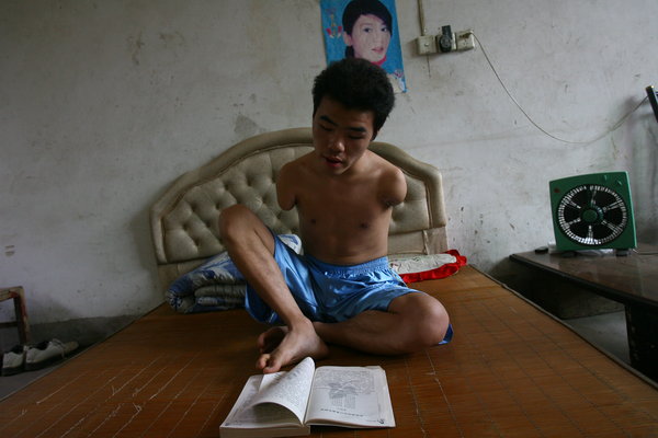Wu Jianping, a 22-year-old who lost both arms in an accident when he was five years old, studies at home in Qinjiacun village, Henan province, July 11, 2011. Wu received his letter of admission from Zhengzhou University of Light Industry on Tuesday. Armless student realizes college dream