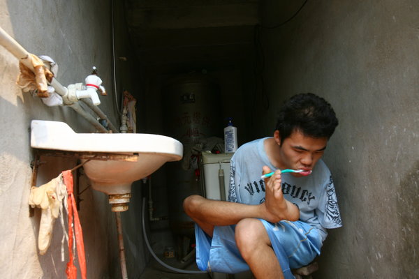 Wu Jianping, a 22-year-old who lost both arms in an accident when he was five years old, brushes his teeth using his feet, July 11, 2011. Armless student realizes college dream