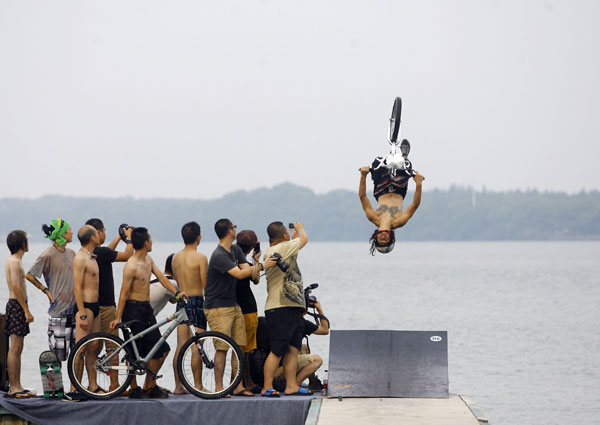 A cyclist turns over in the air before plunging into a lake in Wuhan, July 9, 2012. Cyclists dive into lake in C. China