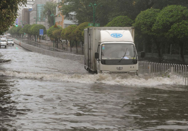 A truck creates a wave of water as it runs through a flooded street in Changchun, Aug 28, 2012. Deadly storm lashes NE China