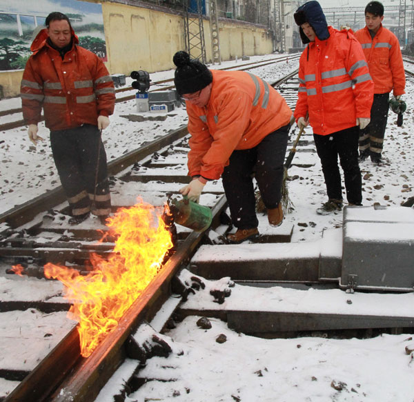 Workers use blast burners to clear ice on railways in Nanchang city, Jiangxi province on Jan 4. South, East China battle against snow