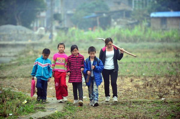 Liang Lina, a 28-year-old CPC branch secretary of Luhe village, walks with students, Feb 25, 2013. Young deputy has high hopes for village