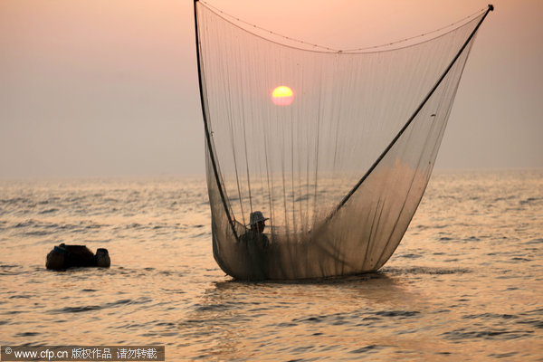 fisherman in Shandong catch shrimps wearing stilts more than one meter in height and use fishing net with rods as long as five meters Fisherman stilted against power of the sea
