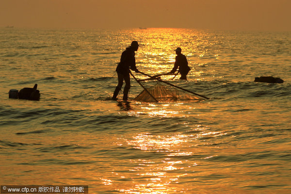 fisherman in Shandong catch shrimps wearing stilts more than one meter in height and use fishing net with rods as long as five meters Fisherman stilted against power of the sea