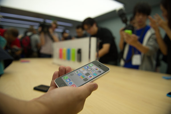 A reporter holds a new iPhone 5C at a media event in Beijing, on Sept 11, 2013. Beijing media gets 1st look at new iPhone 5C