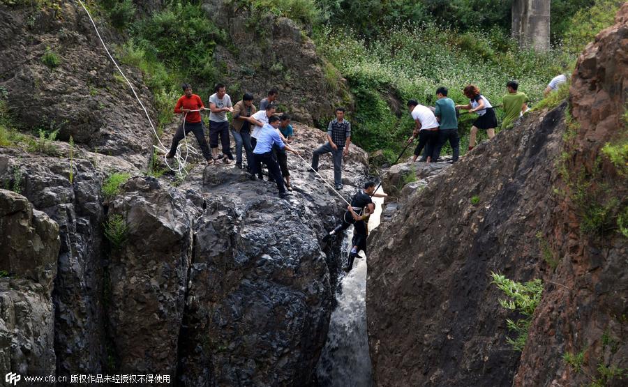 Boy plucked from cliff after falling into waterfall in SW China