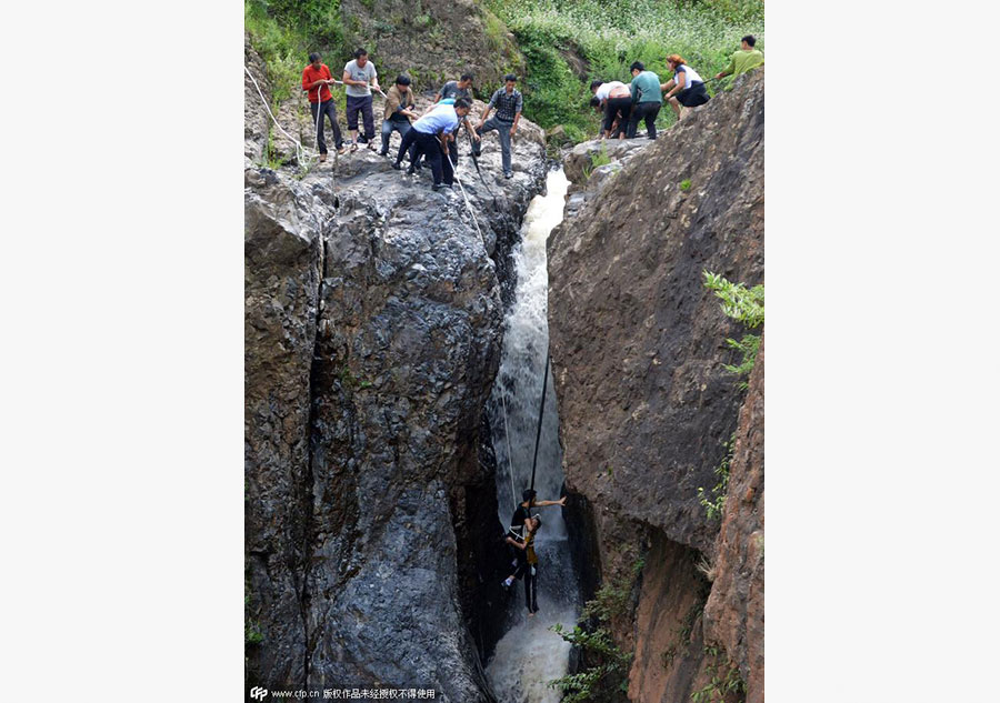 Boy plucked from cliff after falling into waterfall in SW China