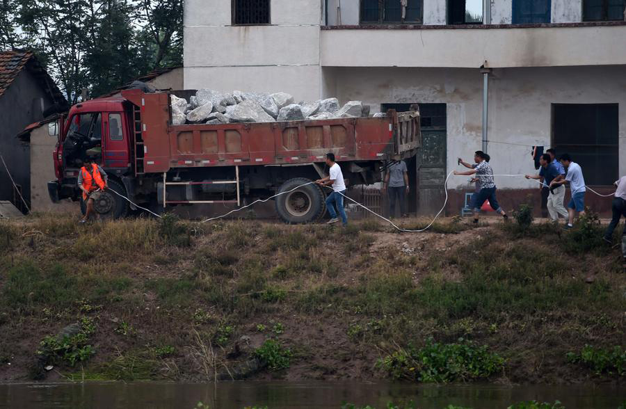 Rescuers risk life, drive heavy trucks to block floodwater