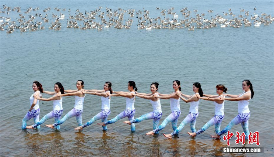 Yoga lovers stretch next to Poyang Lake