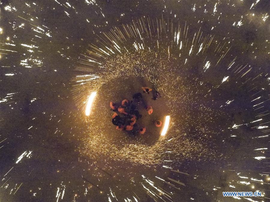 Performers spray burning iron chips to shower sparks-like fireworks