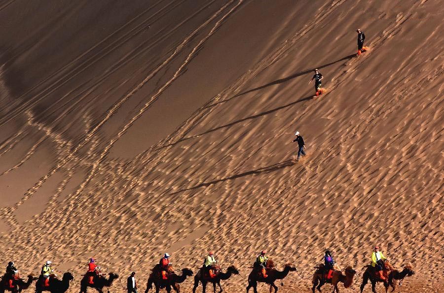 Tourists enjoy themselves at Mingsha Hill desert