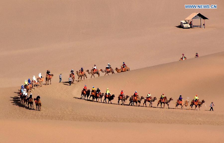 Tourists try camel riding at Mingsha Hill desert