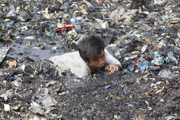 Manila slum-dwellers wade through debris after fire