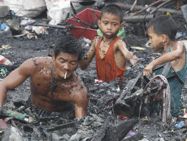 Manila slum-dwellers wade through debris after fire