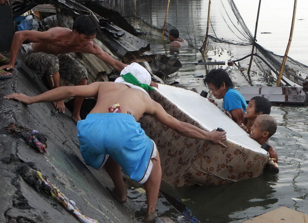 Manila slum-dwellers wade through debris after fire