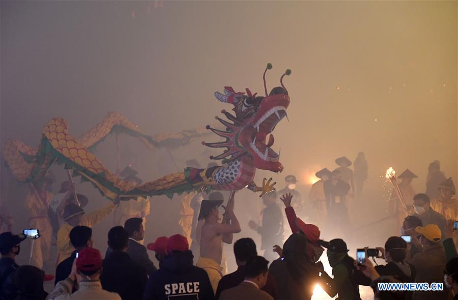 People perform dragon dance in flames of firecrackers in Guangxi