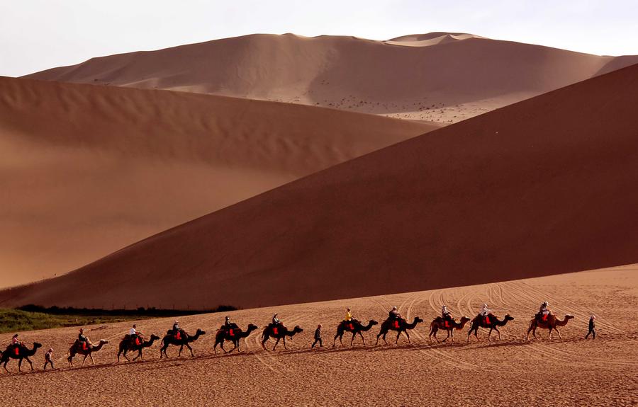 Tourists try camel riding at Mingsha Hill desert